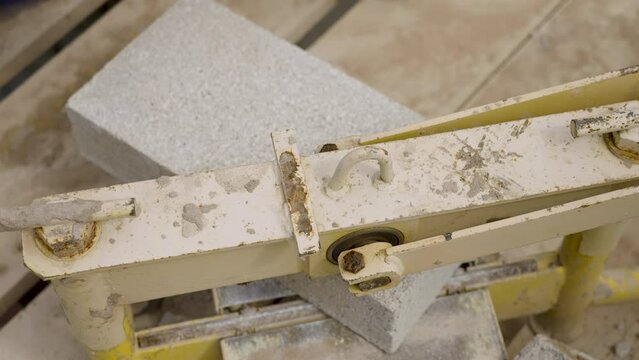 UK - a builder splits a large breeze block in half with a splitter
