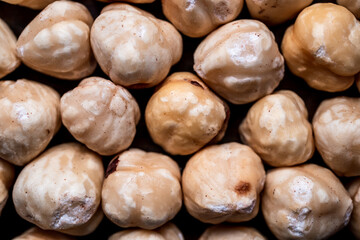 top macro shot of stacked hazelnuts with black background, top shot of unshelled hazelnuts lined up in a row