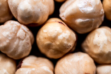 top shot of unshelled hazelnuts lined up on black background, detailed shot of roasted hazelnuts