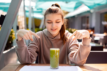 teenage girl drink healthy fresh drink in sunny morning in cafe. focus on girl face