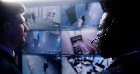 Multi ethnic employees control CCTV cameras with AI facial recognition in police monitoring center....