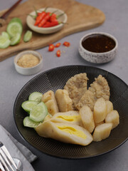 Pempek Palembang, an Indonesian traditional cuisine made from fish cake served with sweet spicy sour sauce and diced cucumber. Piled on white plate on the table