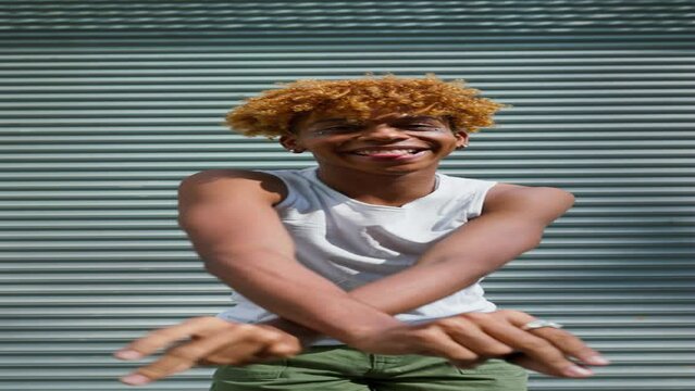 Young stylish hipster black man with makeup in casual clothes dancing outdoor