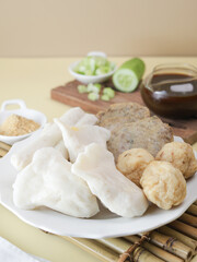 Pempek Palembang, an Indonesian traditional cuisine made from fish cake served with sweet spicy sour sauce and diced cucumber. Piled on white plate on the table