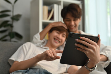 The male couple seemed to enjoy living at home and using tablet together, Focus on tablet.