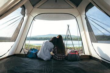 Asian LGBTQ+ couples sit romantically on their shoulders inside a camping tent, LGBTQ couples sit and admire nature, rivers, forests, tent atmosphere inside a camping tent., LGBTQ lesbians, lesbians.