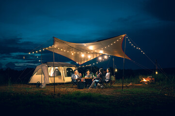 Asian LGBTQ+ couple drinking and barbecue in a romantic camping setting. Groups of friends and...