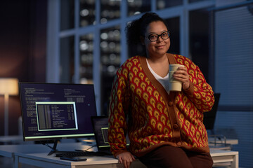 Portrait of African American programmer looking at camera while working till late night in office...