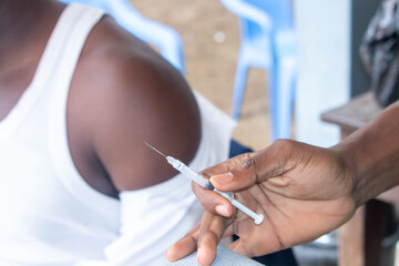 A close-up image of a healthcare professional gently pressing a vaccine needle against a man's shoulder, ready to administer the injection.  .