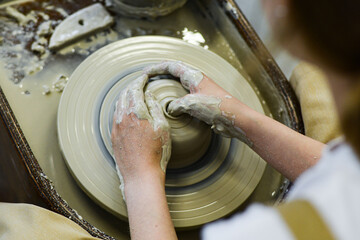 Fototapeta premium close up view of professional potter working on pottery wheel at workshop. High quality photo