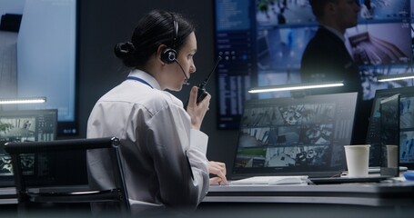Female security officer works on computer in police monitoring center with CCTV cameras video...
