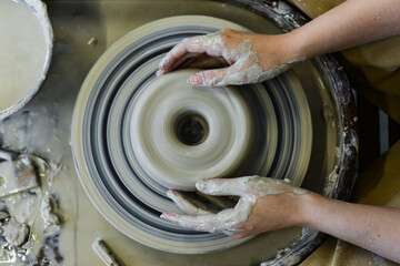 Fototapeta premium close up view of professional potter working on pottery wheel at workshop. High quality photo