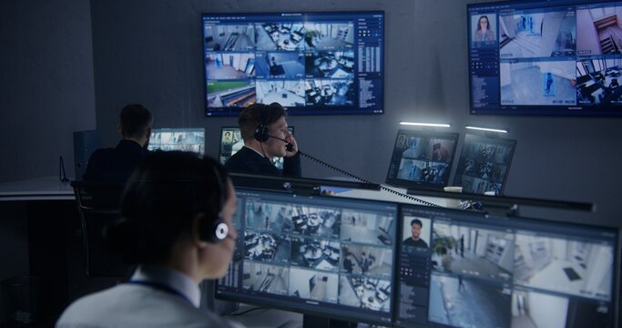 Female security officer watches security cameras with AI facial recognition with male colleagues. Monitoring center workers. Computer monitors and big digital screens with CCTV cameras video footage.