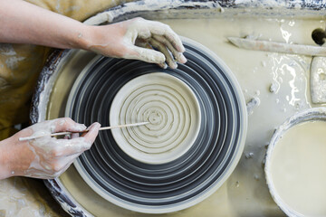 Fototapeta premium close up view of professional potter working on pottery wheel at workshop. High quality photo