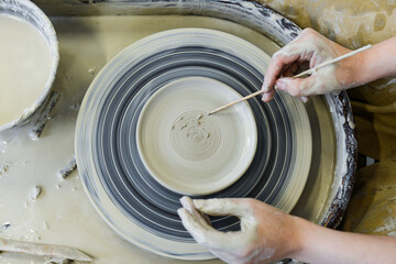 Fototapeta premium close up view of professional potter working on pottery wheel at workshop. High quality photo