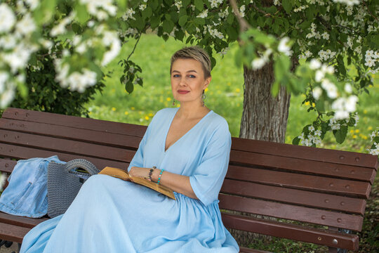 Portrait of a middle-aged woman in a blue dress sits on a bench