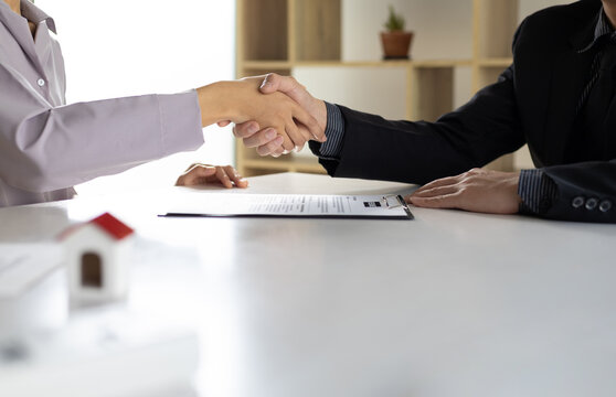 Business, career and placement concept - image of employer sitting in office and shaking hand of young asian woman after successful negotiations or interview.