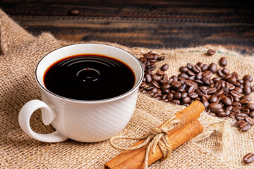 Freshly brewed coffee. Coffee cup or mug arranged on a black wooden table with roasted coffee beans. Espresso mocha cappuccino barista on dark background