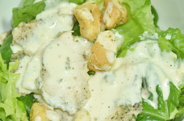 Caesar salad with slice boiled black pepper chicken breast topping crispy bread on bowl