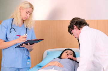 A doctor is examining a patient lying on the bed.