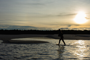 Jovem desfrutando da natureza na margem do rio ao anoitecer 