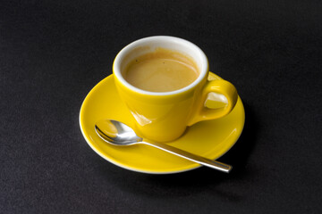 High angle view of sun flower yellow espresso cup with saucer and silver colored spoon against black background. Photo taken May 17th, 2023, Zurich, Switzerland. - Powered by Adobe