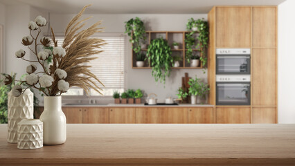 Wooden table, desk or shelf close up with ceramic vases with cotton flowers over modern kitchen with houseplants, urban jungle interior design concept