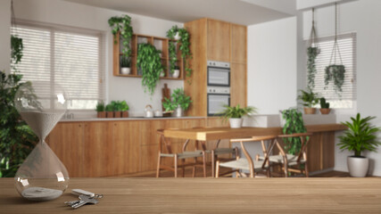 Wooden table or shelf with crystal hourglass measuring the passing time over minimal dining room and kitchen, sofa, house plant interior design, copy space background