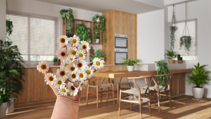 Woman's hand holding daisies, spring and flowers idea, over kitchen and dining room with houseplants, urban jungle interior design