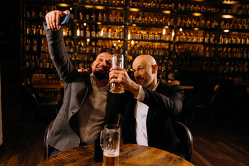 friends drinking beer and taking selfie with smartphone in bar or pub. male friendship - happy.