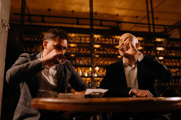 Friends toasting each other with shots of vodka as they enjoy a relaxing night out together at the pub