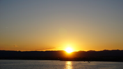 sun on the water and the mountains before setting