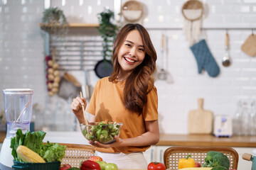 Young Asian woman is preparing a fresh healthy vegan salad with many vegetables in the kitchen, Dieting Concept. Healthy food Lifestyle. Cooking At Home.