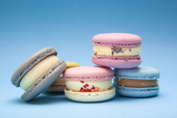 Different colors macarons on blue background, beautiful dessert and sweet food