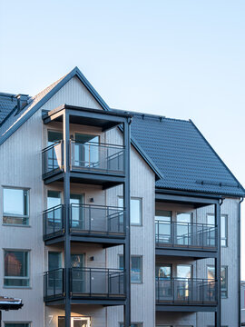 Modern multi floor apartment building with balconies and tiled roof