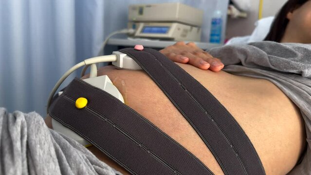 Belly of pregnant woman with electrocardiogram checkup for newborn baby. Process of delivery baby with fetal heart monitoring. Healthcare diagnostic and medical service while childbirth. Natural ligh