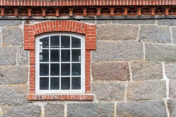The window of the old mansion 19 century with grey stone wall.