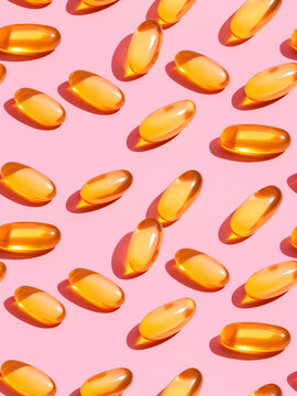 Orange pills scattered on pink surface