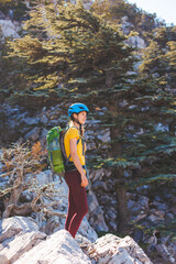 Obraz premium climber with a backpack and a helmet goes along a mountain path in the mountains. Girl climber in the mountains. adventure and mountaineering concept. hiking with a backpack in the mountains.