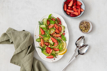 Fresh salad with cucumbers, strawberries on yogurt with pistachios