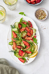 Fresh salad with cucumbers, strawberries on yogurt with pistachios