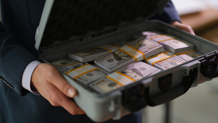 Businessman in suit holding suitcase full of currency money closeup. Profitable financial deals...