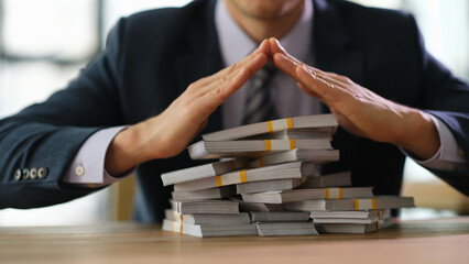 Male banker protecting with hands lot of banknotes closeup. Secure storage of money savings in bank...