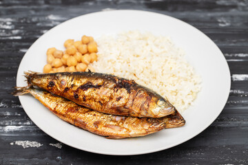 Grilled sardines with boiled rice and chick-pea on plate