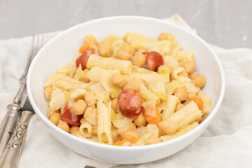 chick pea with smoked sausages, pasta and cabbage in white bowl