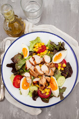 Delicious light vegetable salad made from tomatoes, canned corn, cucumber, lettuce, avocado, boiled egg andchicken