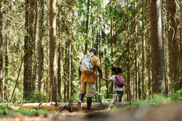 Rear view of family of two with backpacks walking in the forest during hiking