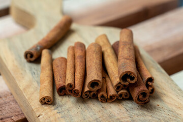 Cinnamon sticks on a cutting board on a wooden background