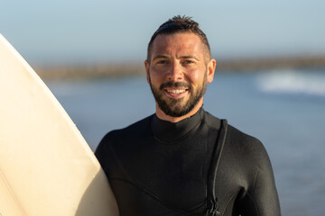 Smiling man surfer in a wetsuit