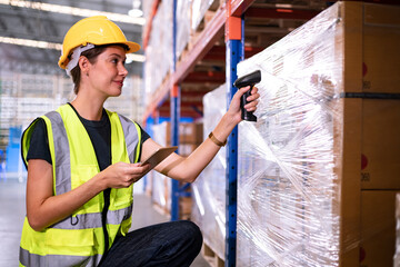 Warehouse worker scanning barcode on box in a large warehouse. Smart woman worker scanning package with barcode scanner while using digital tablet in warehouse.